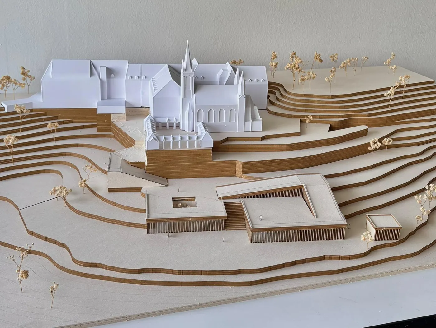 Weißes 3D-gedrucktes Klostermodell mit Kirche und Mauer in einem Geländemodell aus Karton für eine Architektur-Projektarbeit